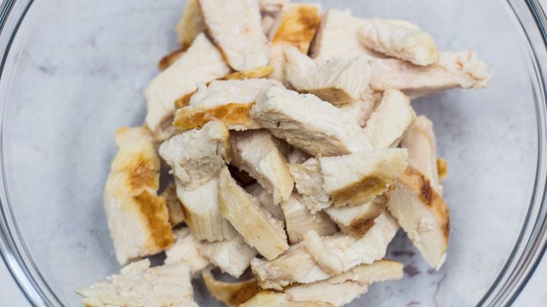 Close up of a bowl of cooked chicken meat cut into strips