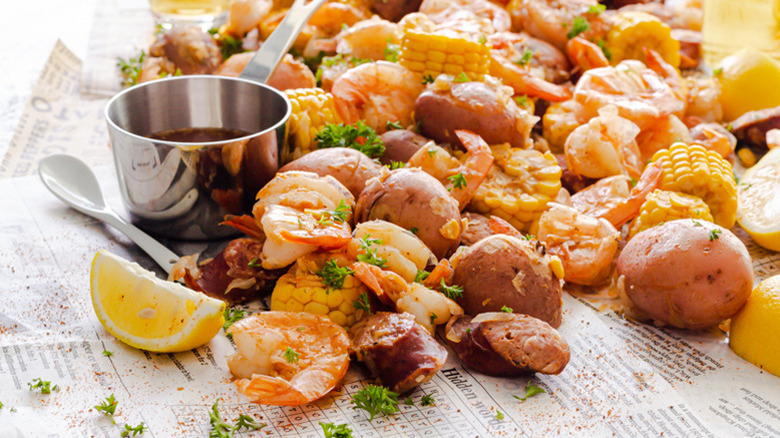 Close up of a metal cup of seasoned butter next to Instant Pot Shrimp Boil