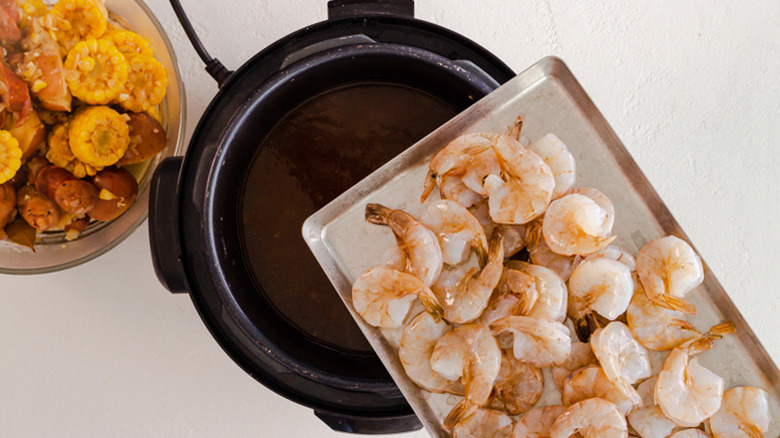 Close up of a tray of shrimp being held over an Instant Pot