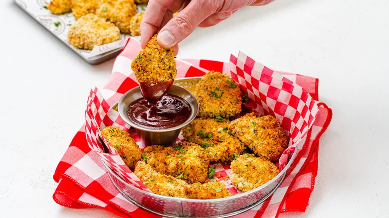 Hand dipping nugget in sauce