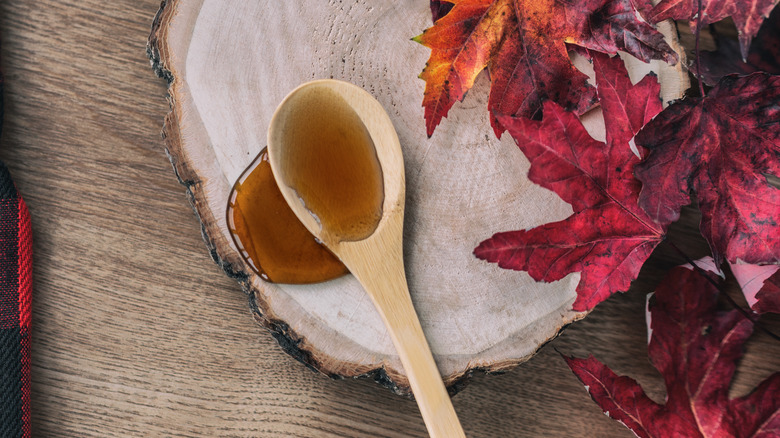 Maple syrup on wooden spoon with maple leaves