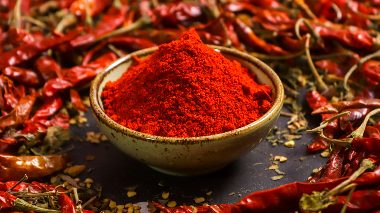 Chili powder in a bowl with dried peppers around it 