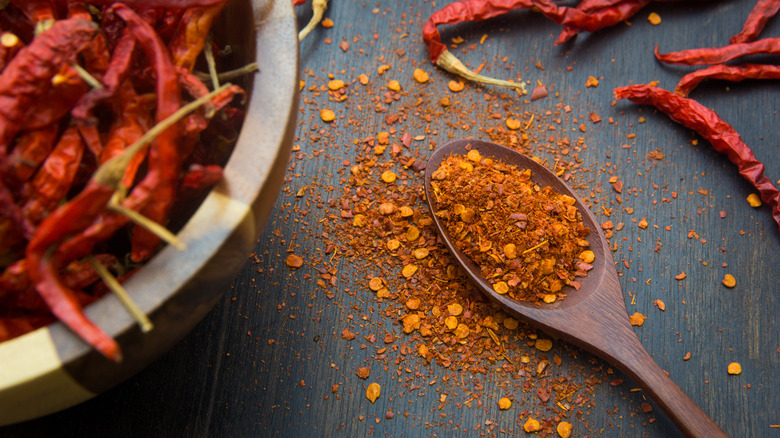 whole and ground cayenne peppers on a wood board