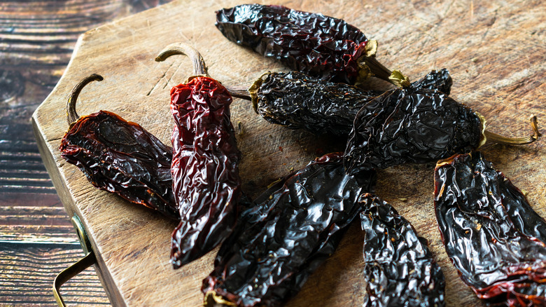 Dried chipotle peppers on a wood cutting board