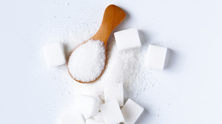 white granulated sugar in spoon and cubes around it