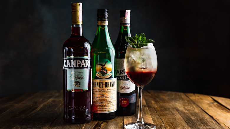 Bottles of Campari and Fernet Branca behind a cocktail