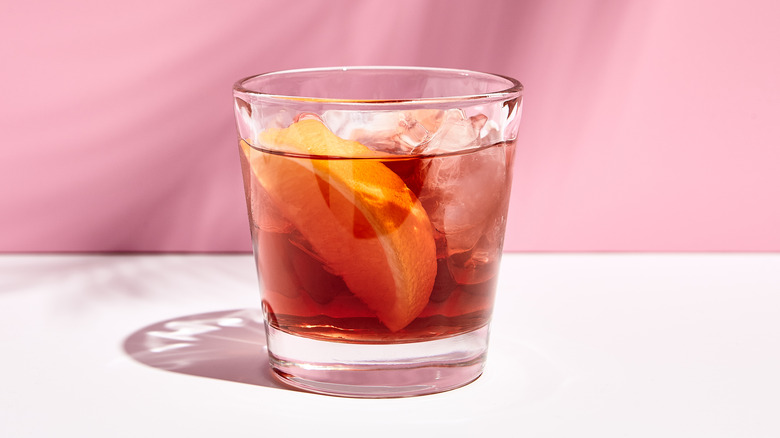 A glass of Negroni with an orange wedge