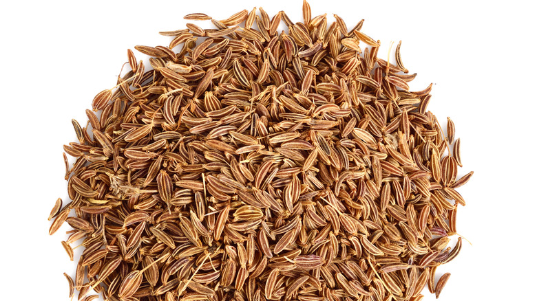 a pile of caraway seeds on a white background