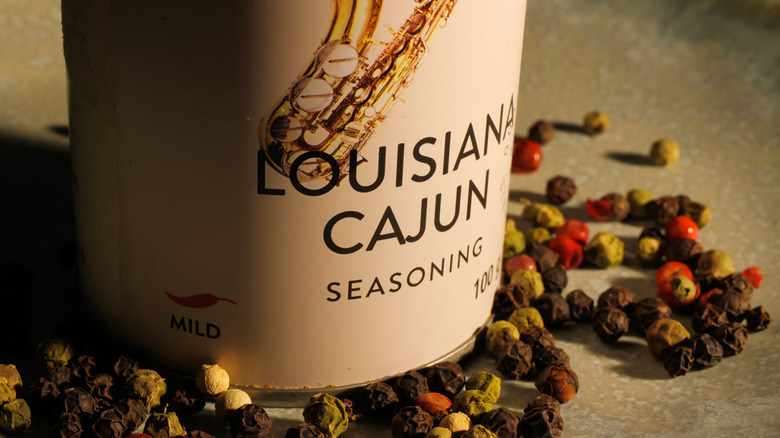 Jar of Cajun spice with peppercorns around it