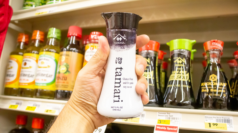 Hand holding bottle of tamari