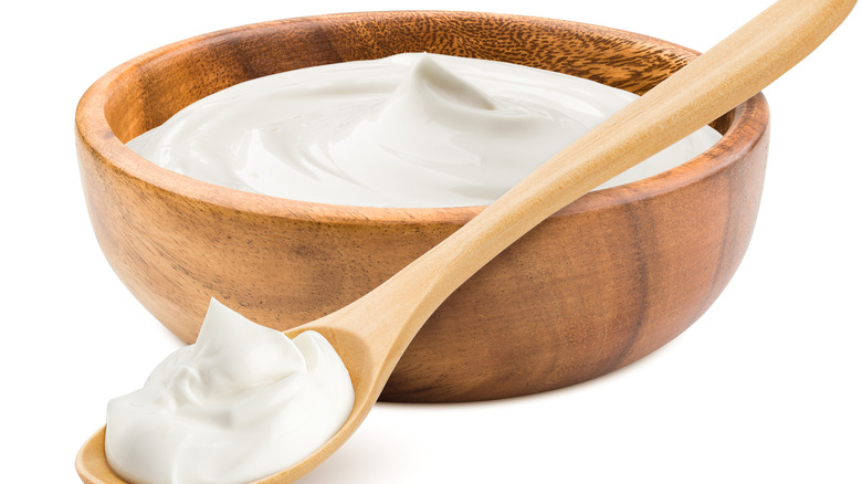 Sour cream in a wooden bowl with wooden spoon