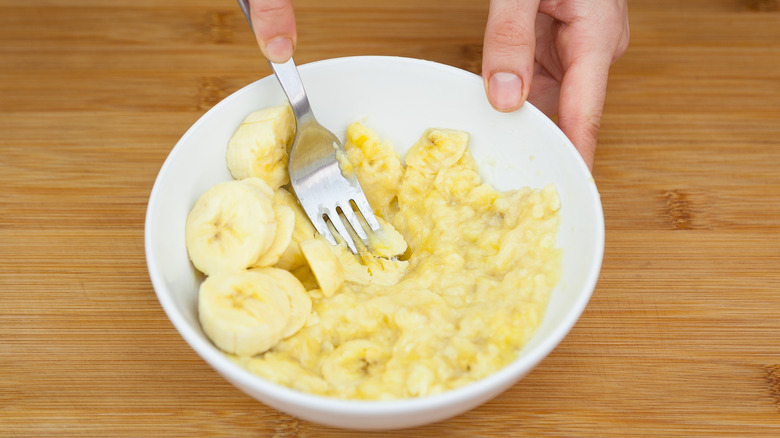 Person mashing up bananas in a bowl