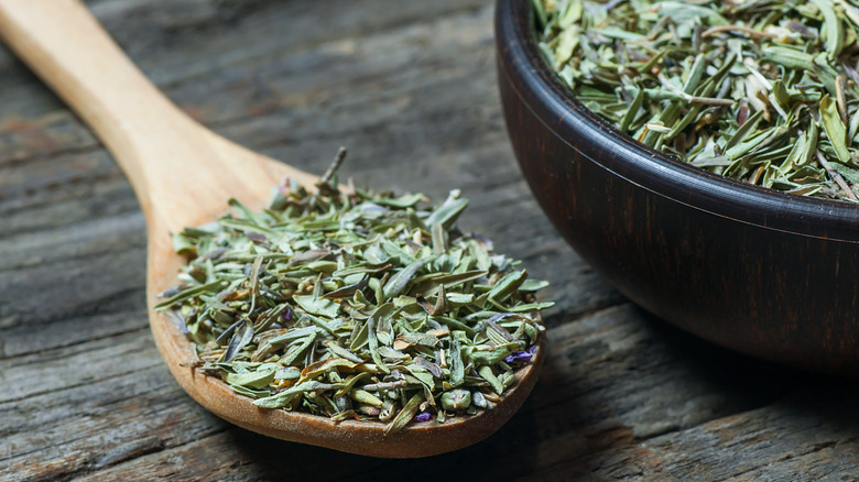 Dried basil and thyme in wooden spoon with bowl