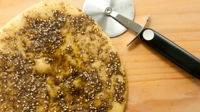Pita bread with za'atar and oil with pizza cutter