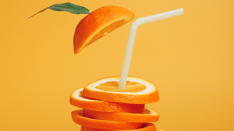 A straw poking out of stacked orange slices 