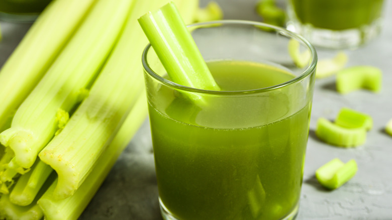 A glass of celery juice with celery stick garnish 