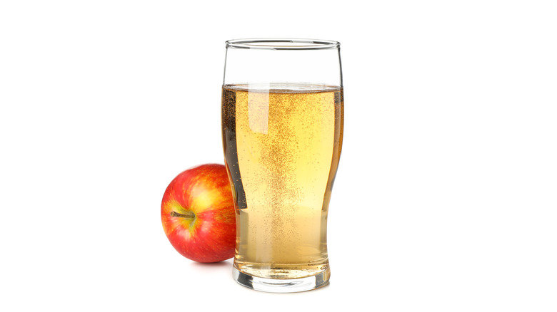 Glass of apple cider next to apple