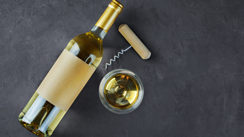 Top down view of white wine bottle, corkscrew, and glass