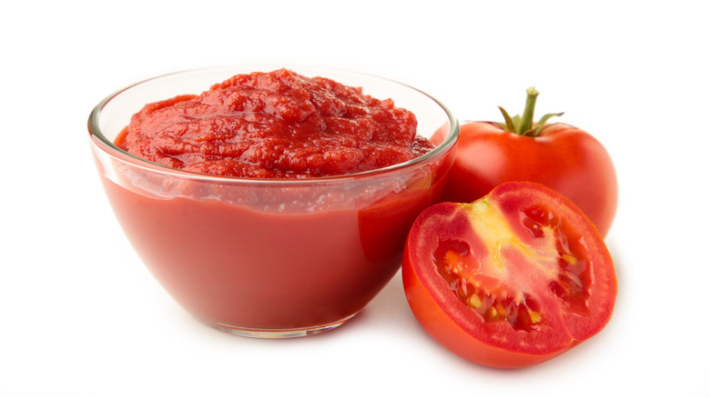 bowl of tomato paste next to raw tomato halves