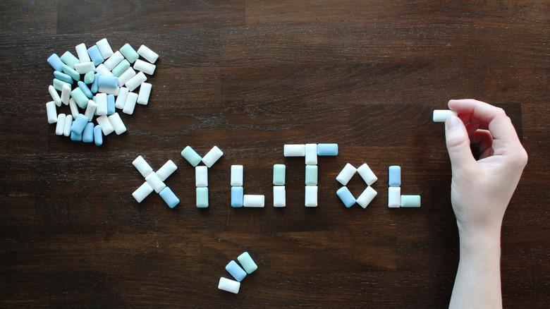 "Xylitol" spelled out in chewing gum on a wooden table
