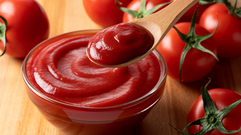 Bowl of ketchup with fresh tomatoes alongside 