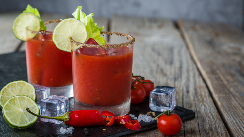 bloody mary's with lime on a wooden surface 