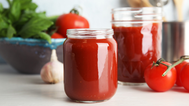 tomato passata in a jars surrounded by fresh tomatoes 