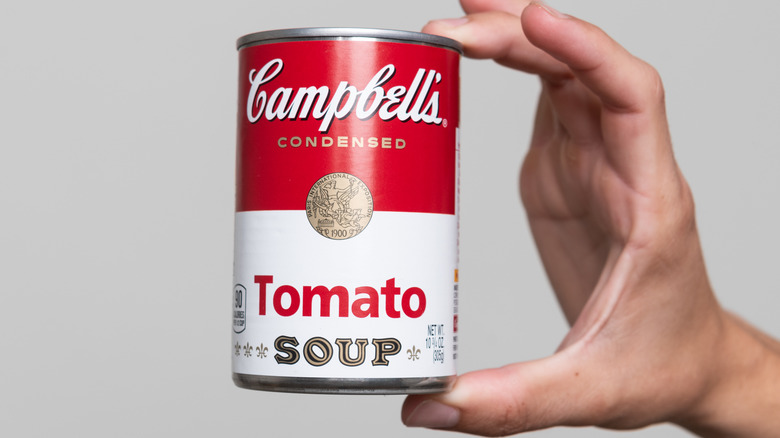 Tomato soup in a can held by hand