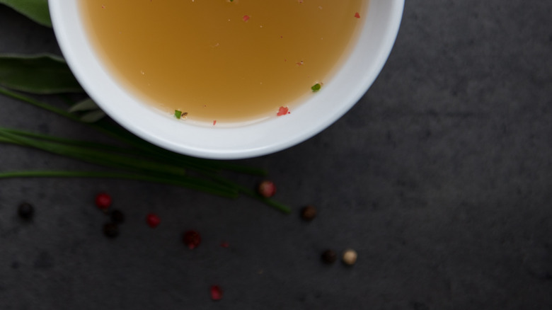 A bowl of vegetable broth on marble slab