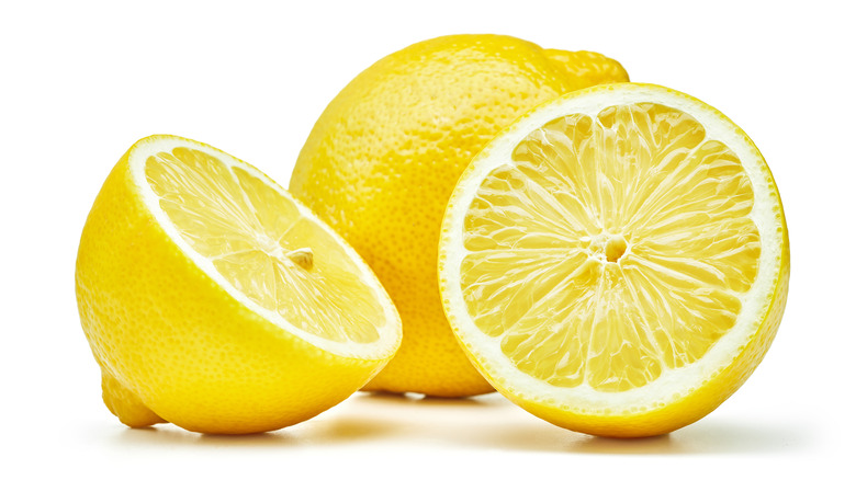 Whole and sliced lemons on white background