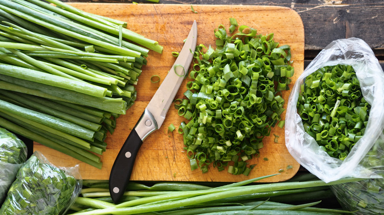 Green onions on a board with a knife