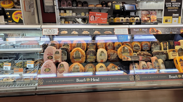 A variety of meats are displayed inside of a deli case.