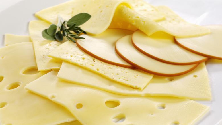 A variety of sliced cheeses is displayed on a plate.