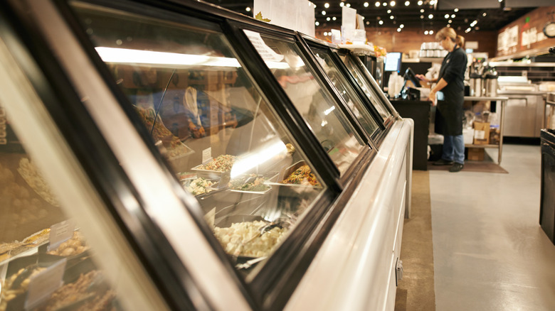 A clean deli case with a worker at the register