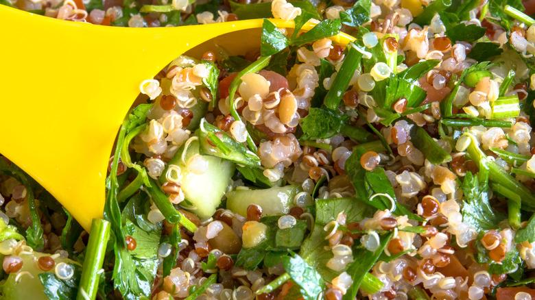 Quinoa salad being scooped with a yellow spoon