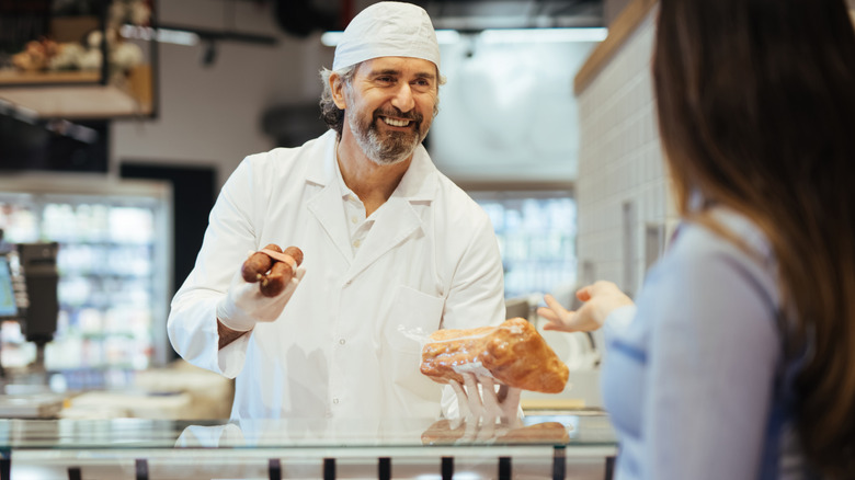 Butcher helping person at counter