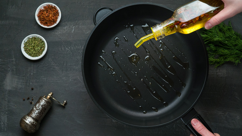 olive oil being poured into a frying pan