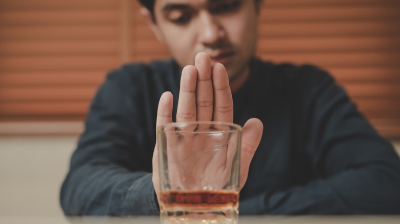 Person with hangover touching glass 