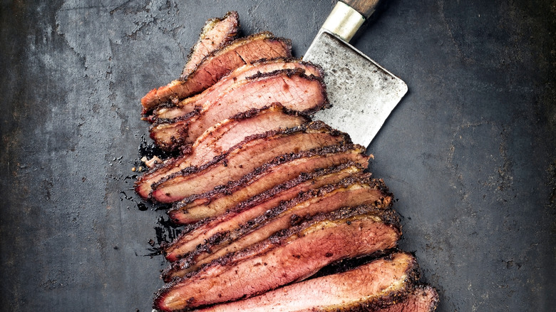 Traditional smoked barbecue wagyu beef brisket offered as top view with knife on an old rustic board