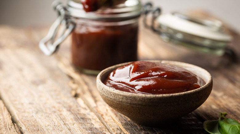 Barbecue sauce in a saucer with basting brush over rustic barn wood table