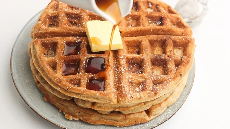 pouring syrup on apple pie waffles with butter on top