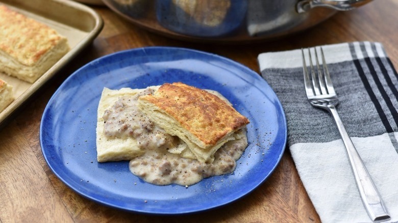 blue plate of biscuits and gravy with fork and napkin