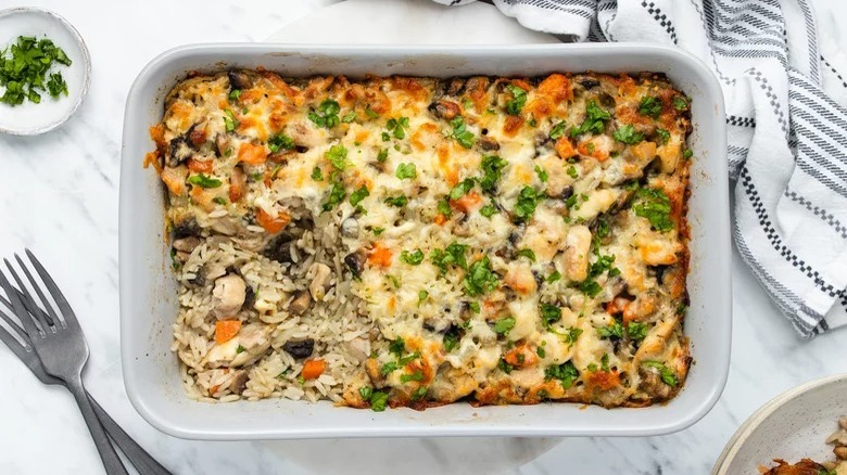 casserole dish of hearty chicken and rice casserole with forks and dish towel