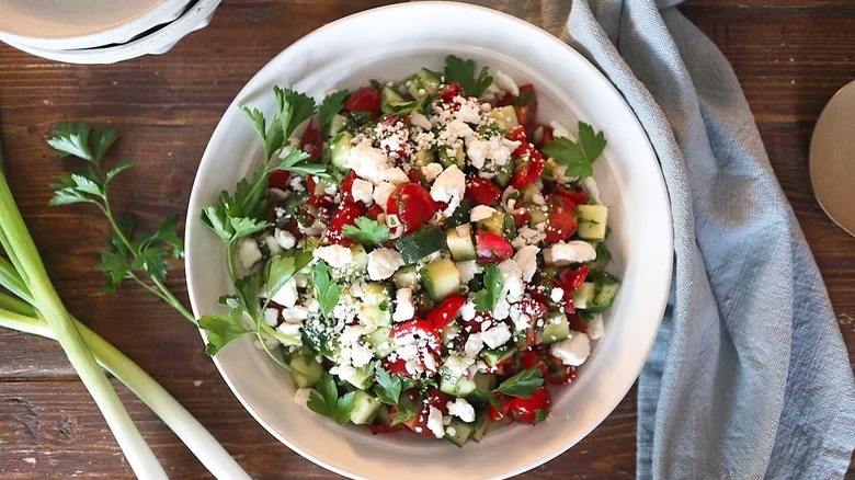 bowl of shepherd salad with cilantro and dish towel