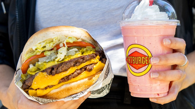 hands holding burger and shake