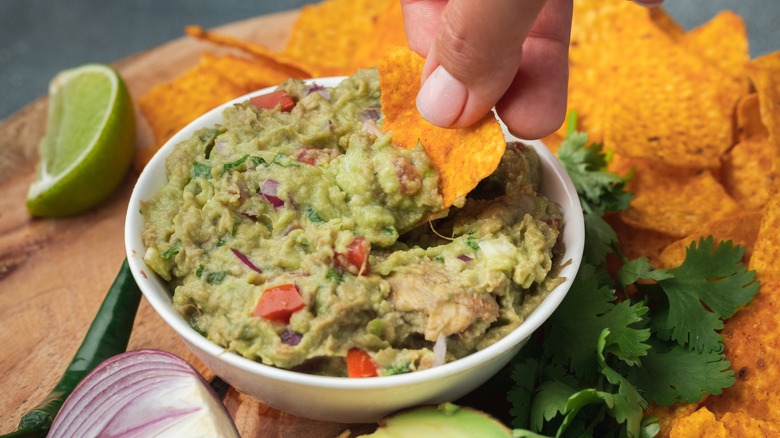 bowl of guacamole with a chip being dipped 