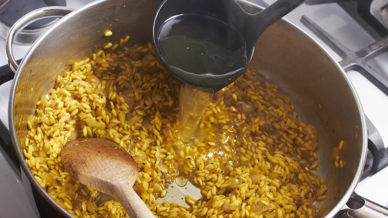 adding broth to risotto