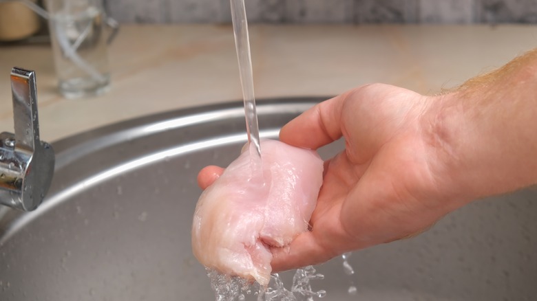 man rinsing off defrosted chicken