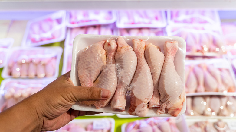 person holding package of chicken in store