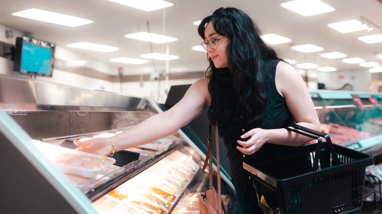 woman reaching for chicken in store